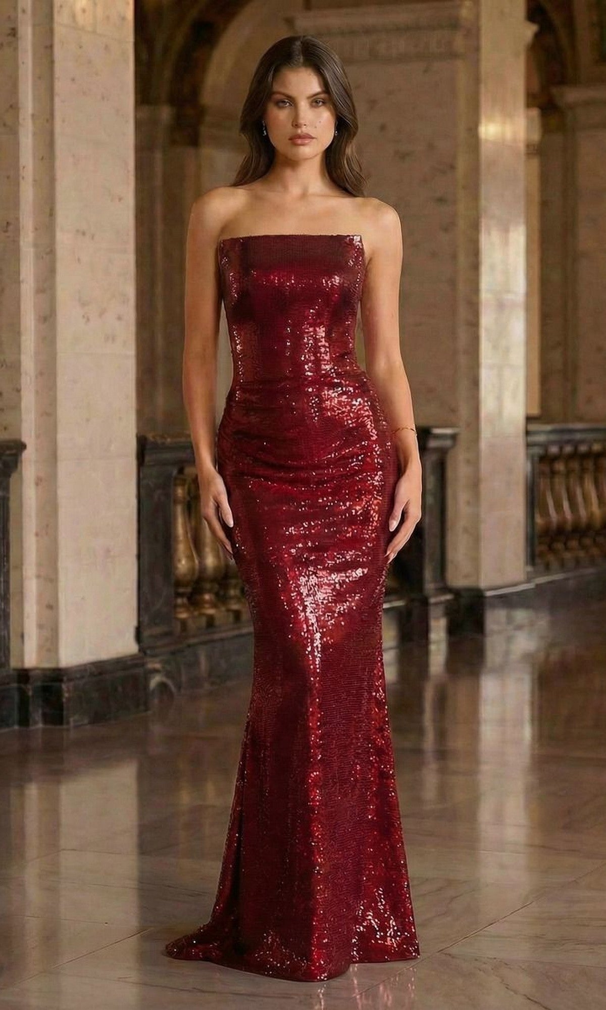 A woman in the Ladivine J904 long prom dress, a strapless sequined burgundy gown, stands in an ornate marble hall with columns and arches, her floor-length dress sparkling beneath grand lights.